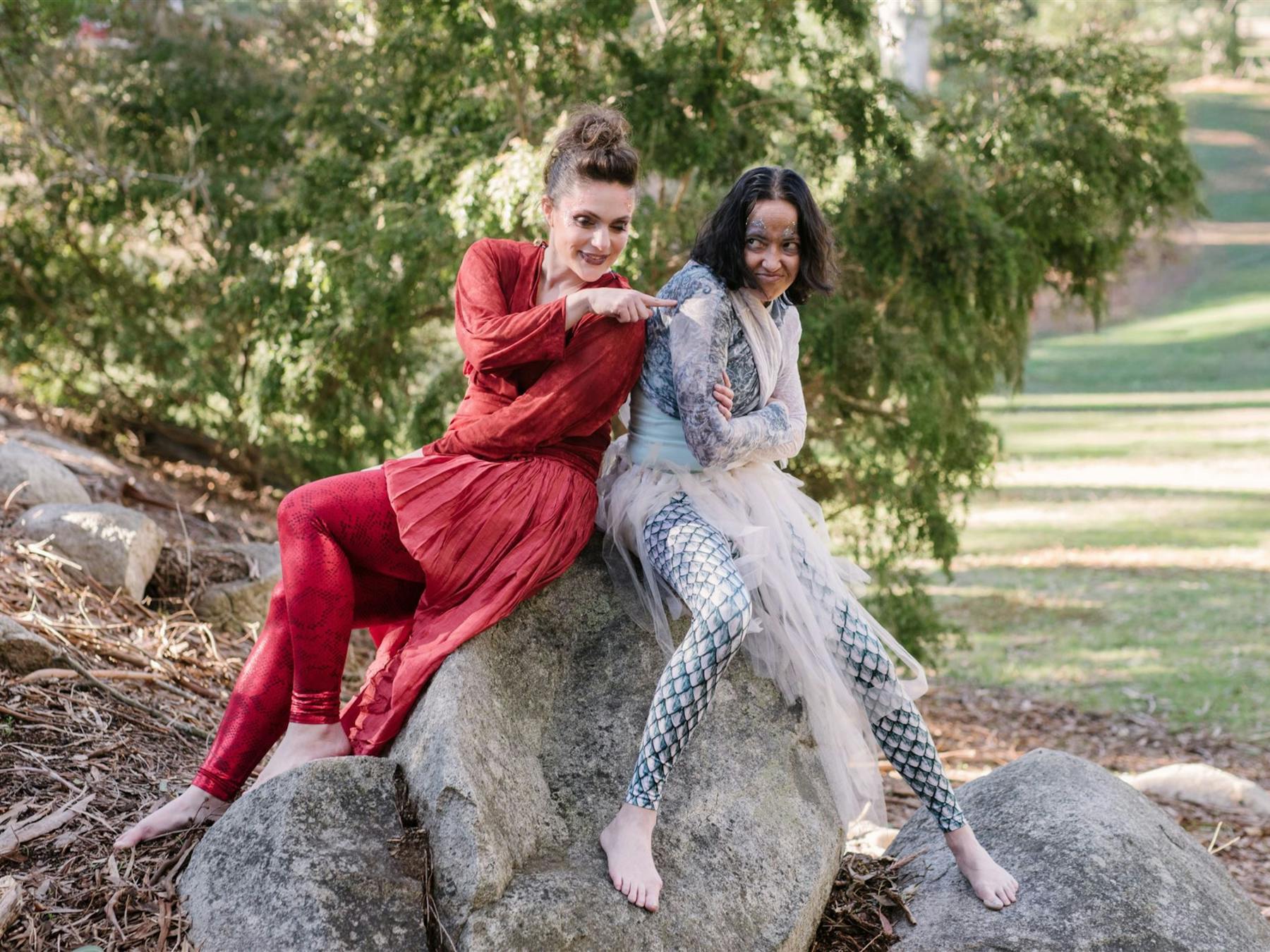 To magical characters playfully interacting, while sitting on a rock