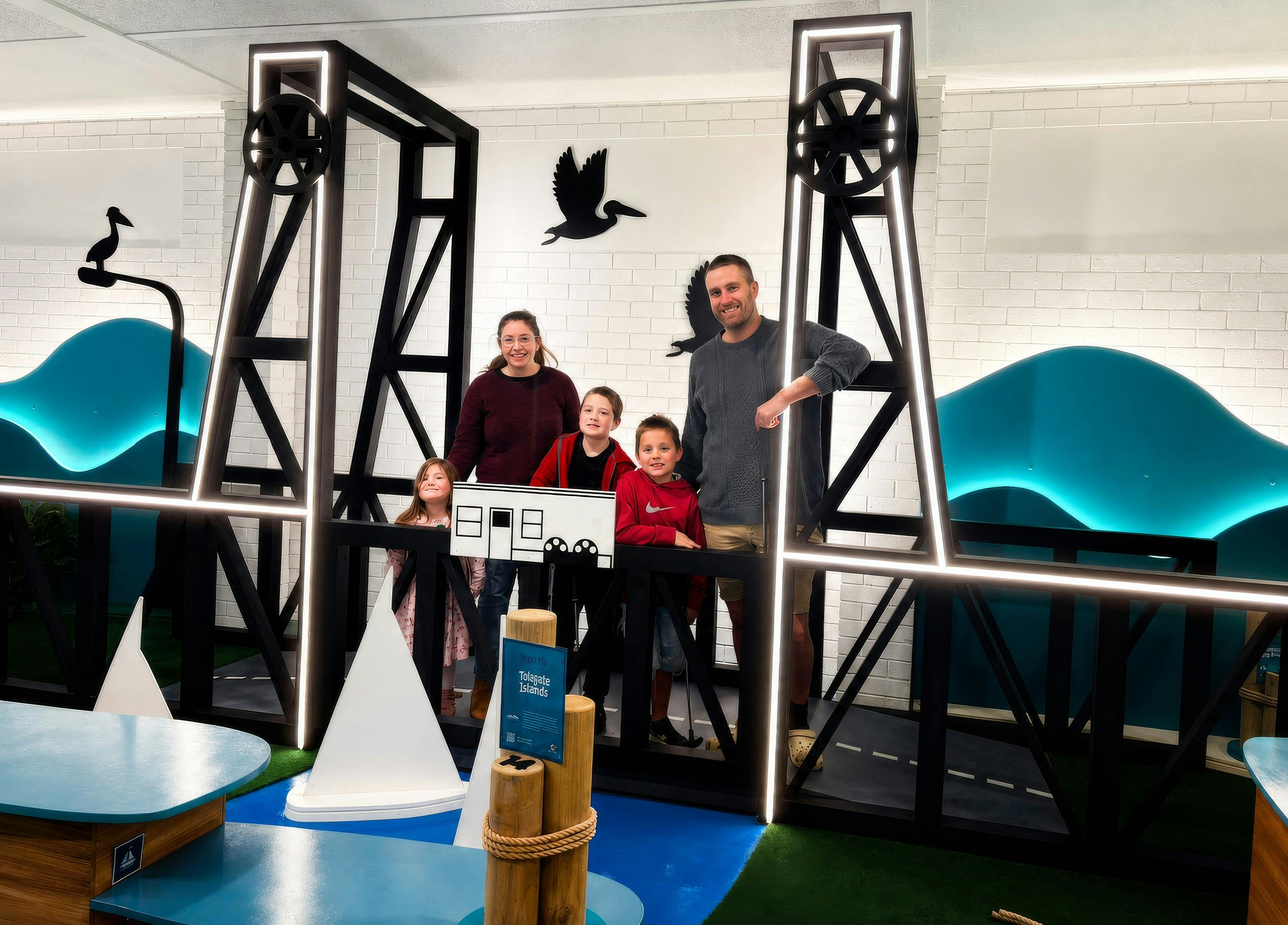 Family standing on the Bay Bridge feature hole at Nice Putt Mini Golf