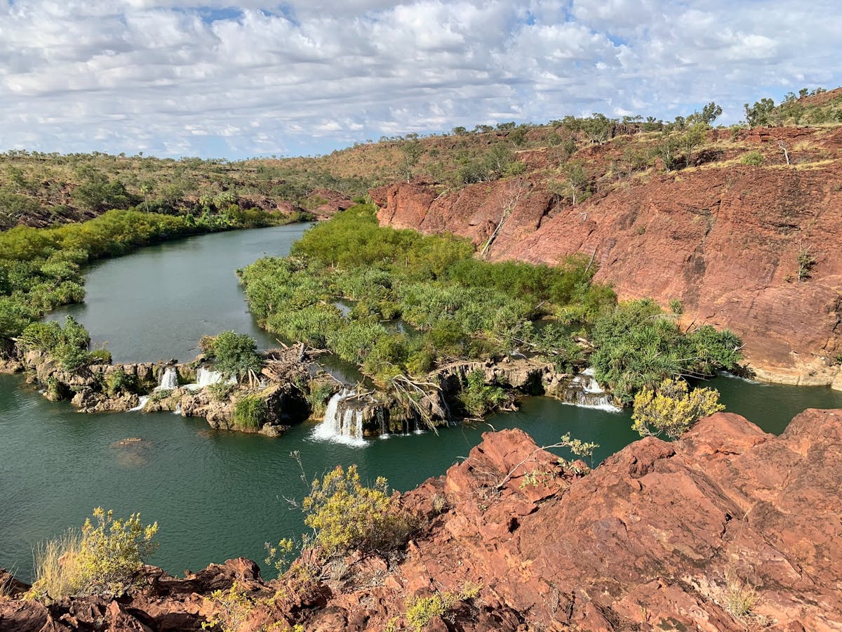 River with small waterfalls over ledges surrounded by red cliff formations