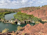 River with small waterfalls over ledges surrounded by red cliff formations