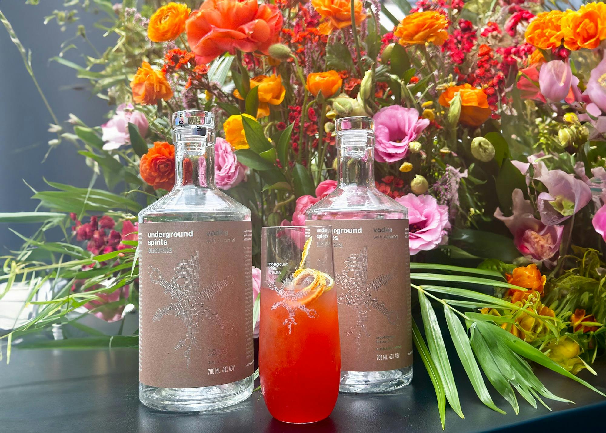 Bottle of Underground Spirits Caramel Vodka surrounded by bright florals