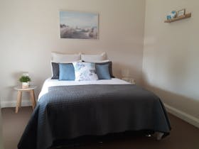 Queen bed, pillows, side tables with reading lamps and styling items, print  on wall
