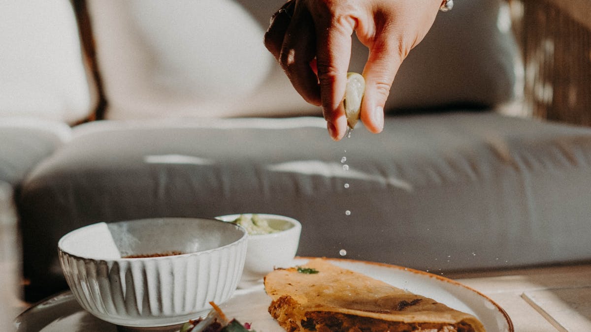 A person squeezing lime onto a taco