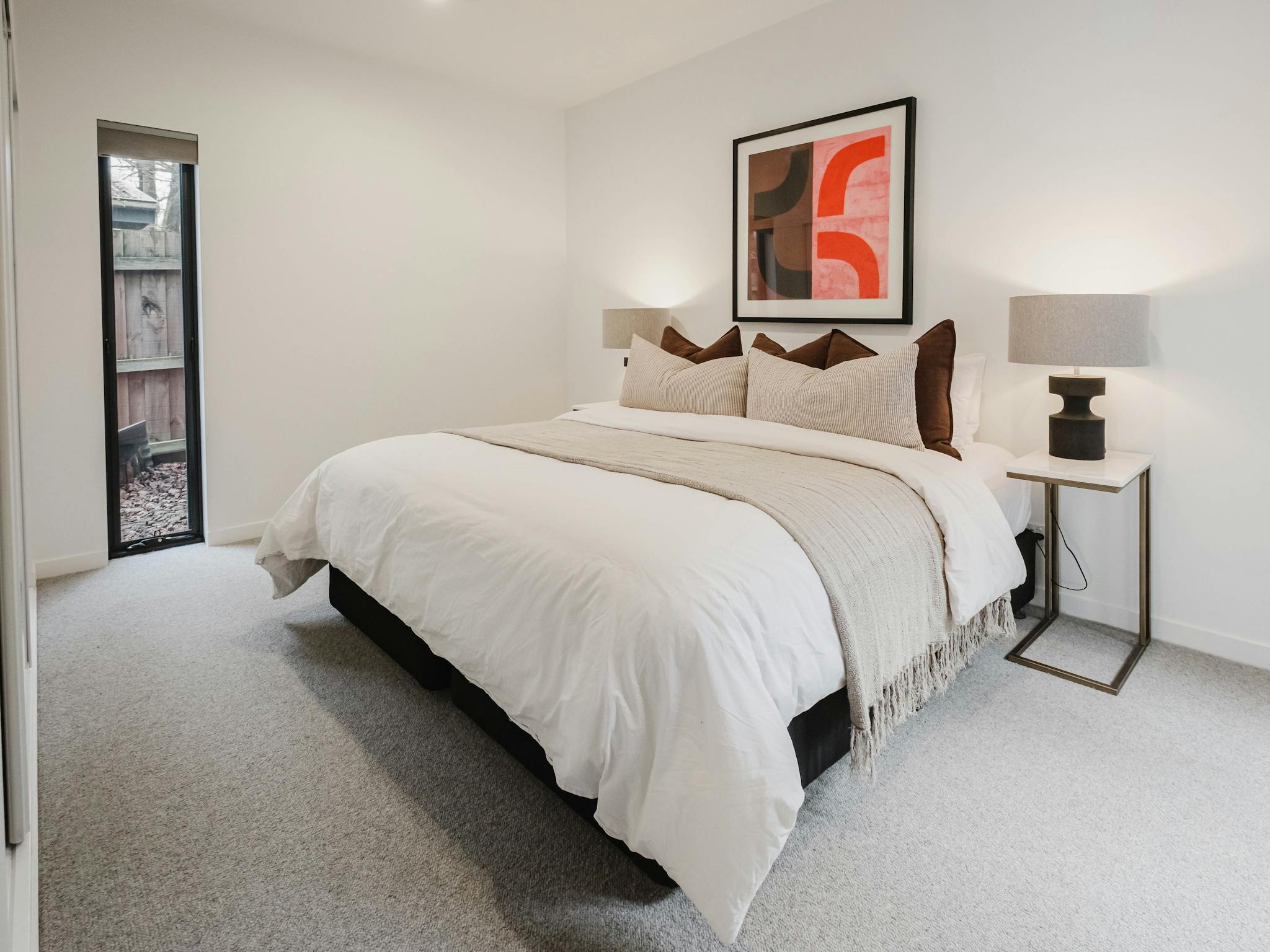 Reed arthouse townhouse bedroom with bed, table side lamps, painting on the wall