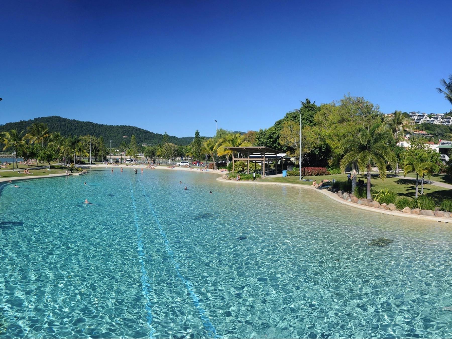 Calm waters of the lagoon pool surrounded by green grass areas and palm trees