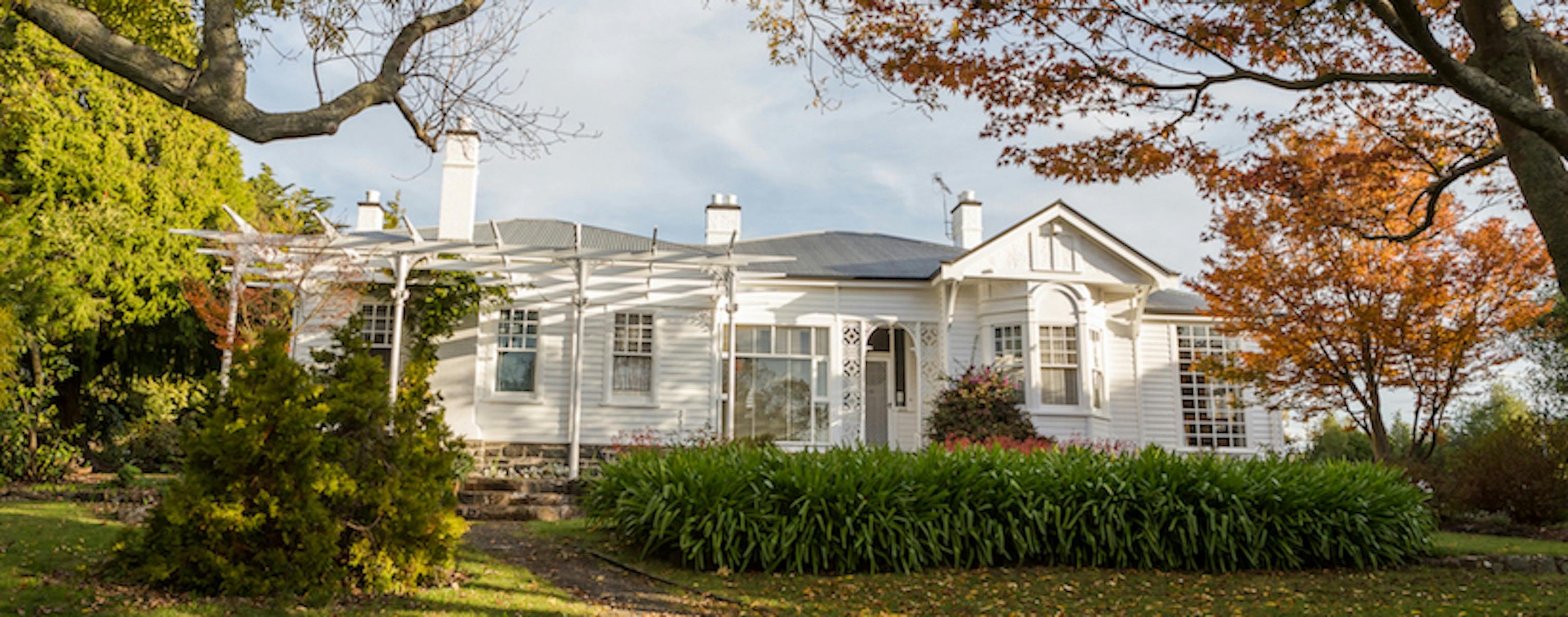 White weatherboard house with autumn trees