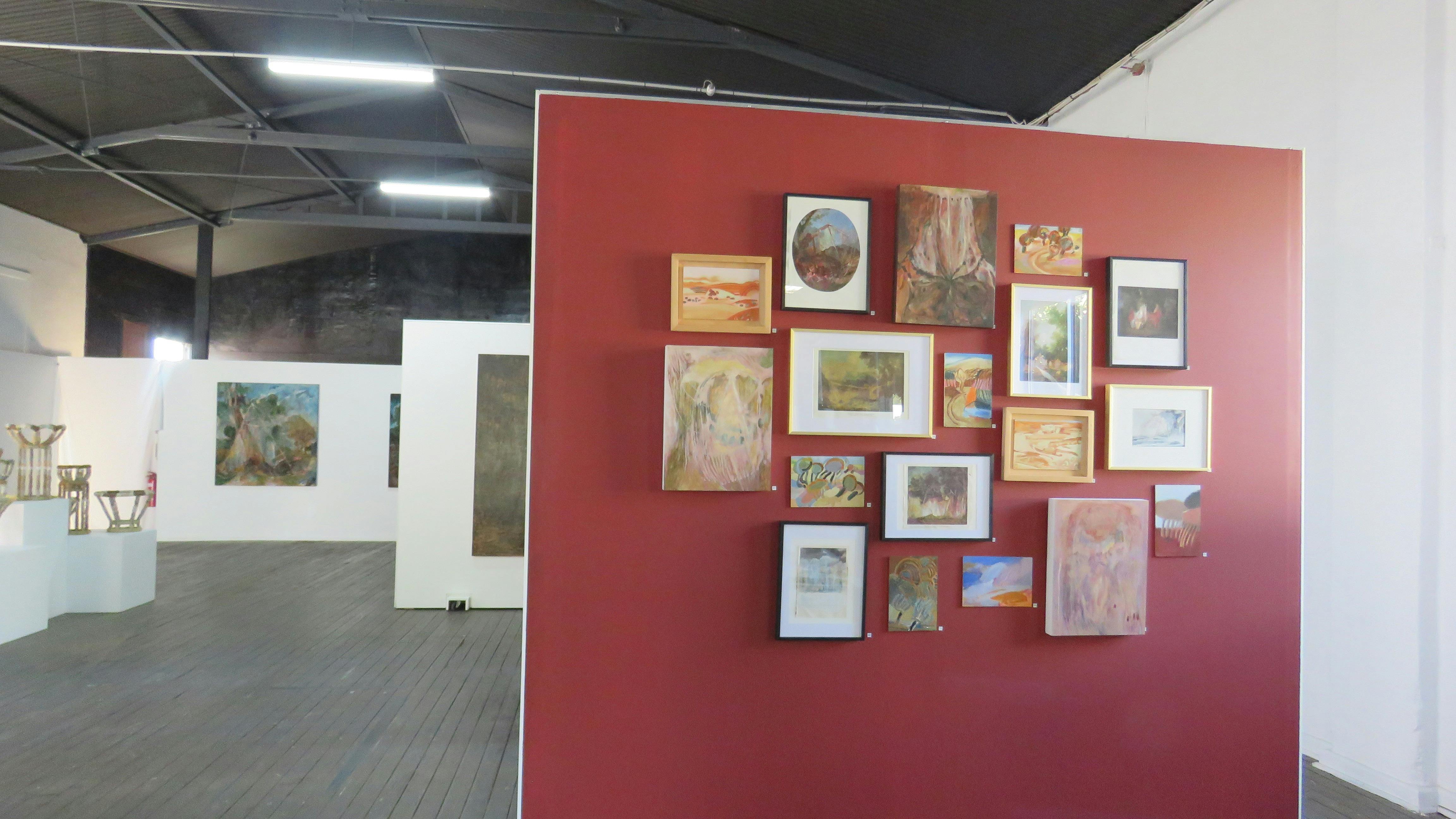 gallery space with red feature wall and framed paintings