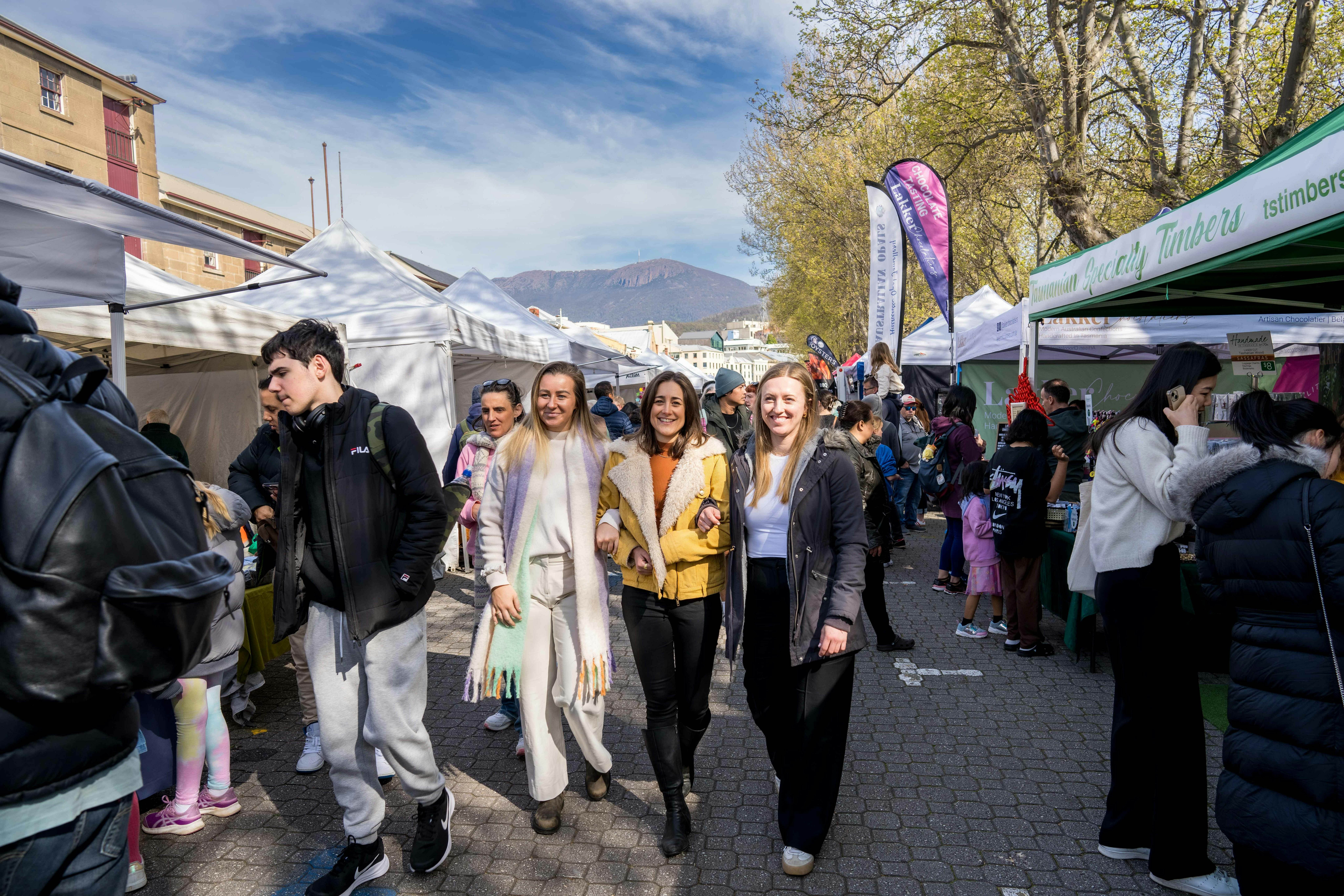 Three girls with linked hands walk through the market