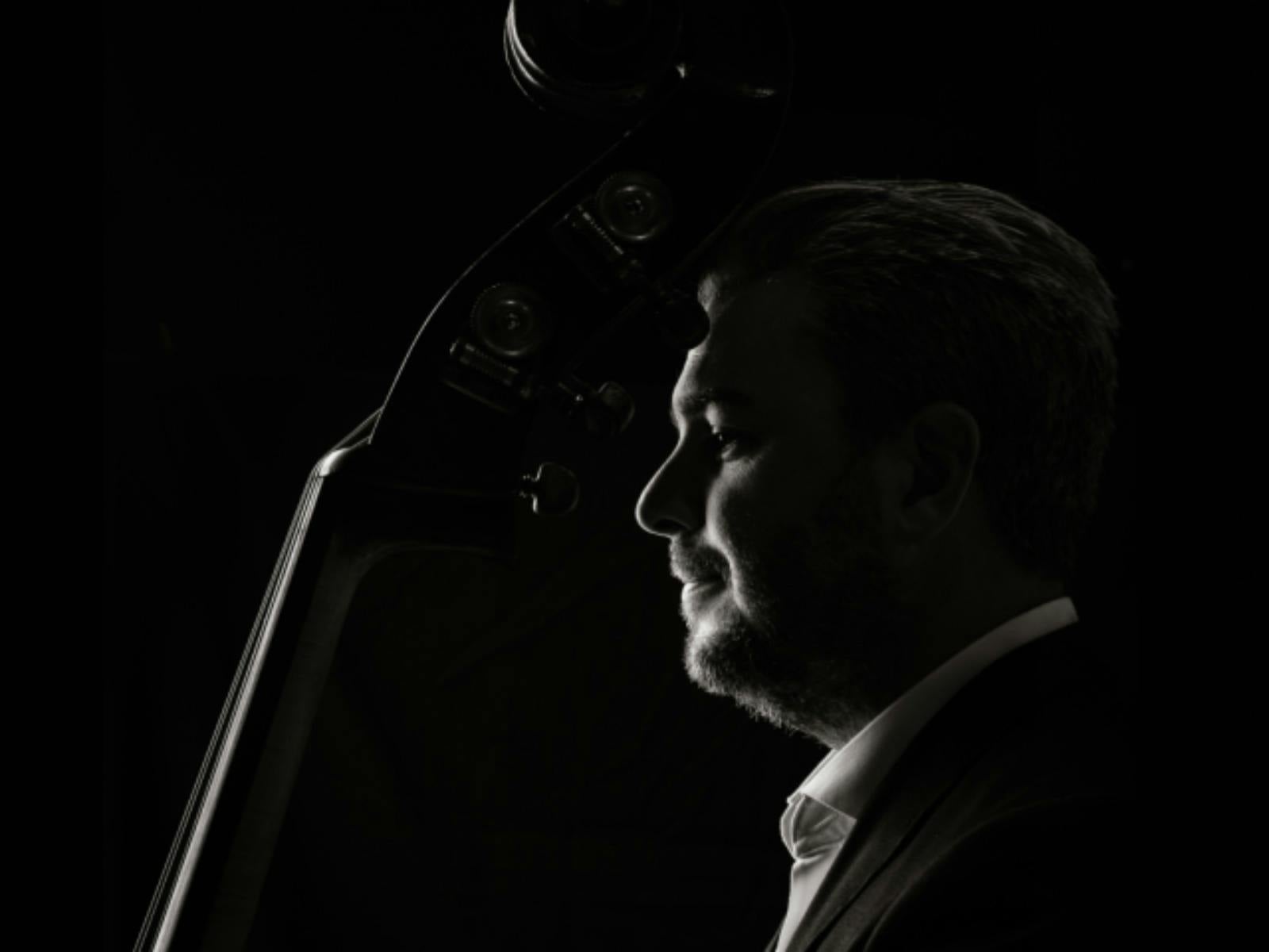 Black-and-white portrait of a double bass player in profile, looking toward the light Black-and-white portrait of a double bass player in profile, looking toward the light