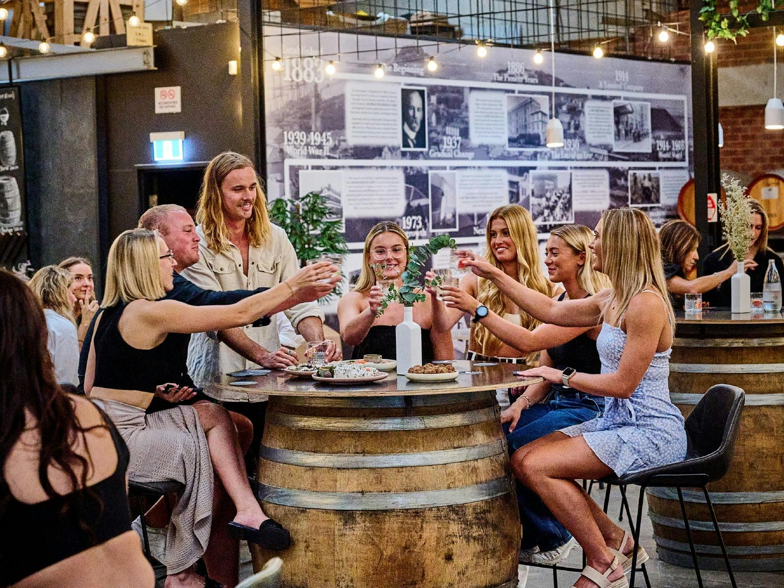 한 무리의 젊은이들이 통 주위에 앉아 안경을 환호하고 있습니다.