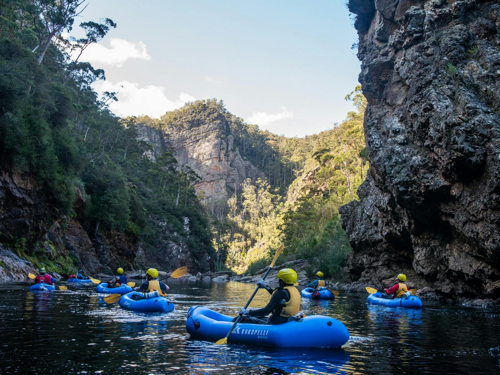 A group paddling packrafts through a gorge in Tasmania