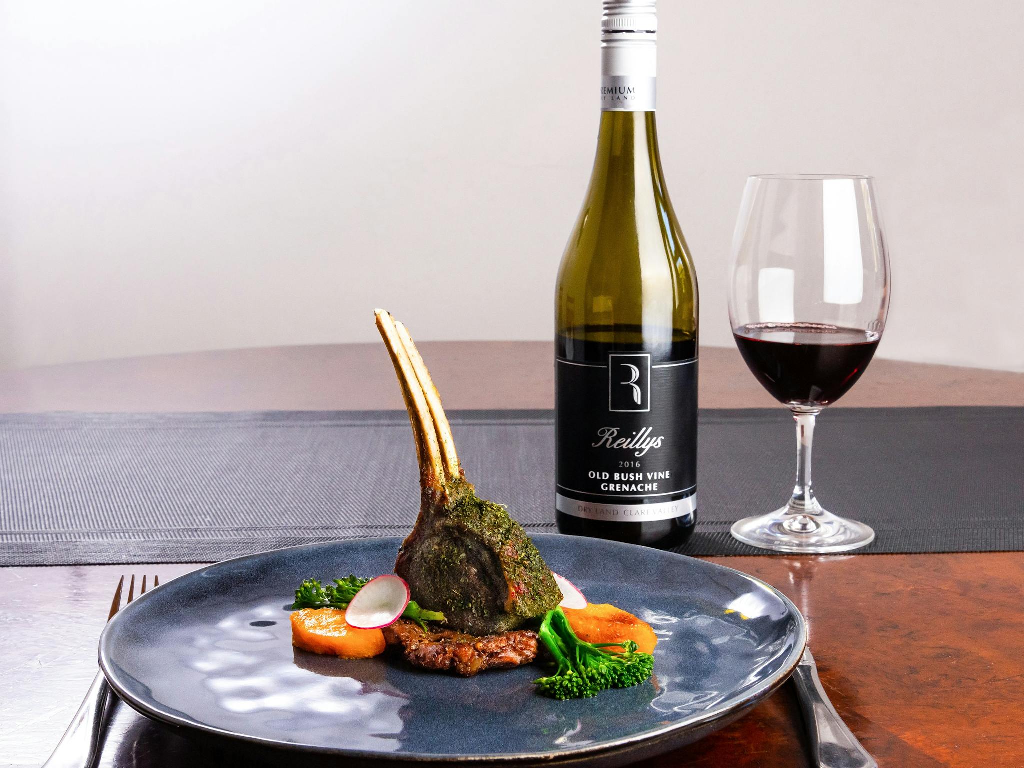 Herb crumbed lamb cutlet standing up on a bed of roasted vegetables