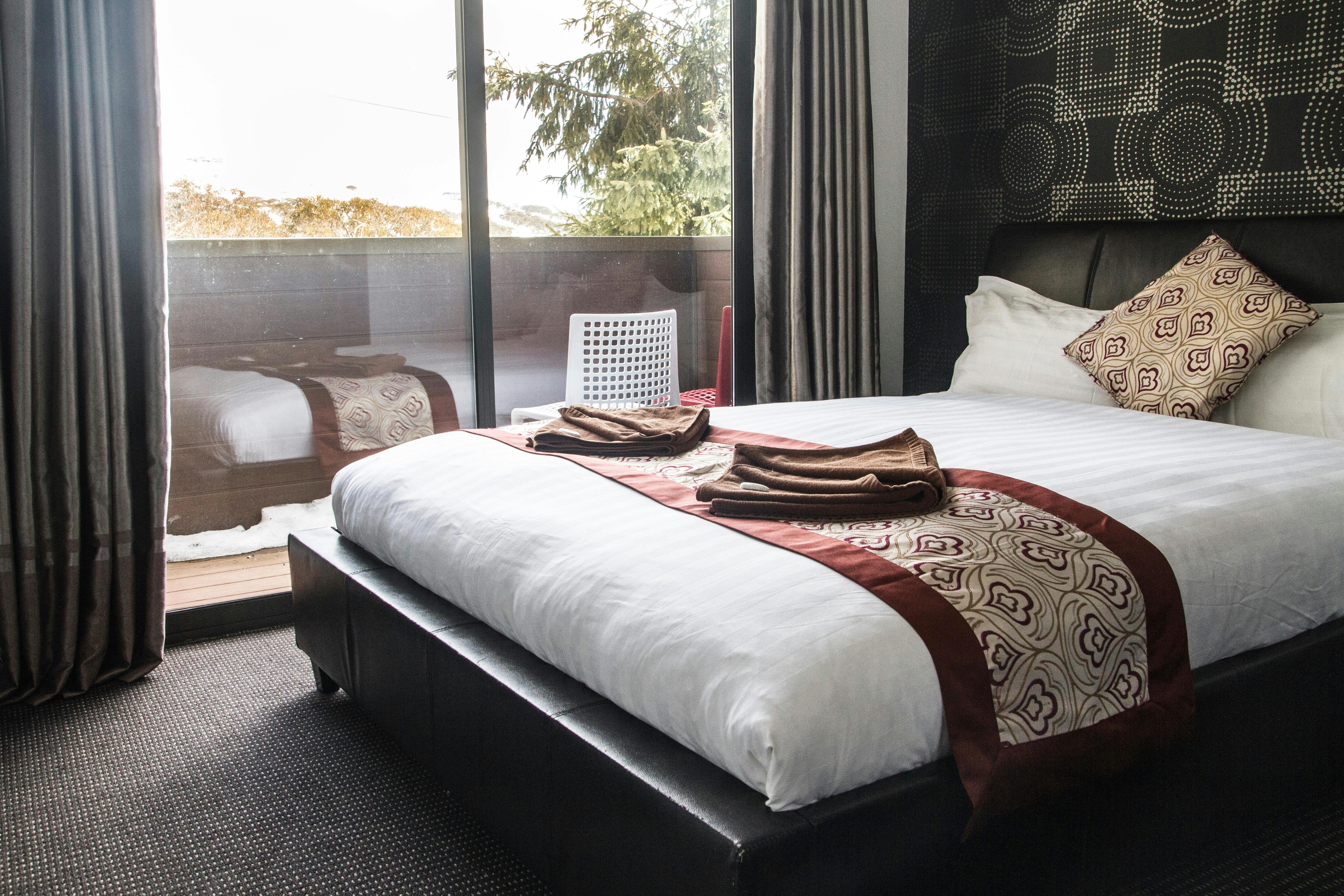 double bed inside a room with glass door leading to balcony