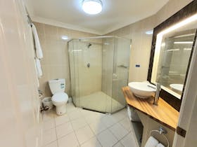 Large bathroom with corner shower and timber vanity
