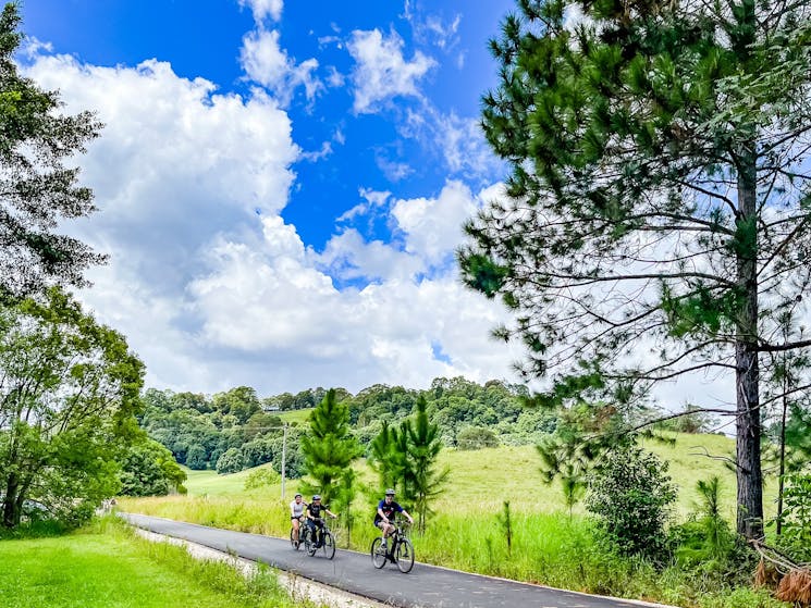 Three riders on E Bikes, in open country approaching camera on the Northern Rivers Rail Trail