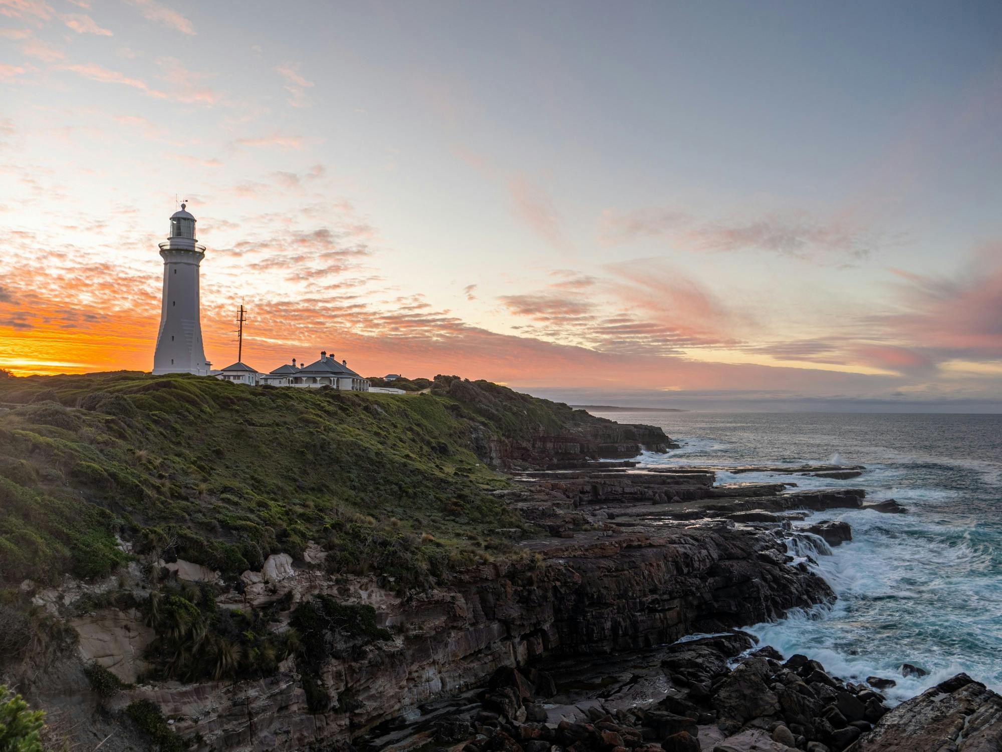 The sunsets colours of orange behind green cape lighthouse