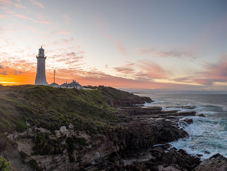 The sunsets colours of orange behind green cape lighthouse