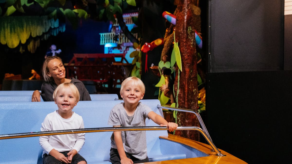 Kids and mum in a floating boat ride, in a jungle scene as part of the Ginger Factory ride