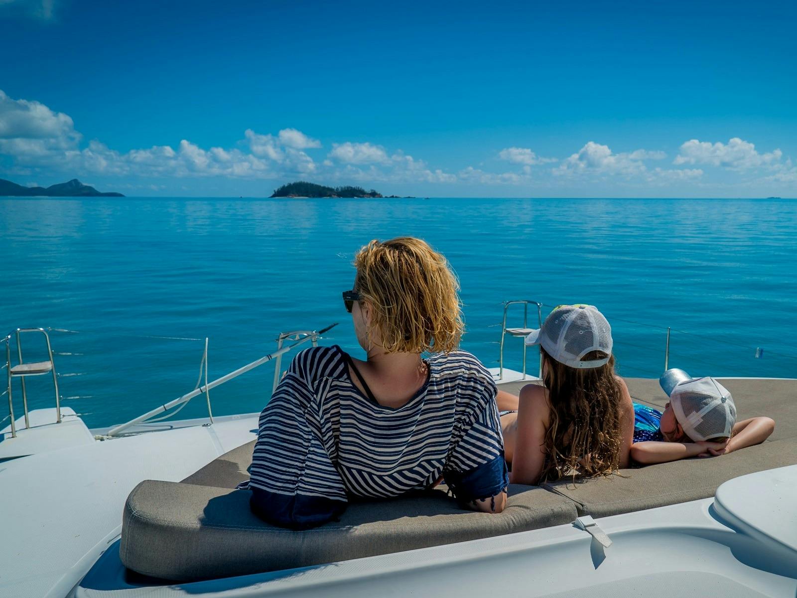 Mum and 2 young children on the bow of a boat in rthw Whitsudays