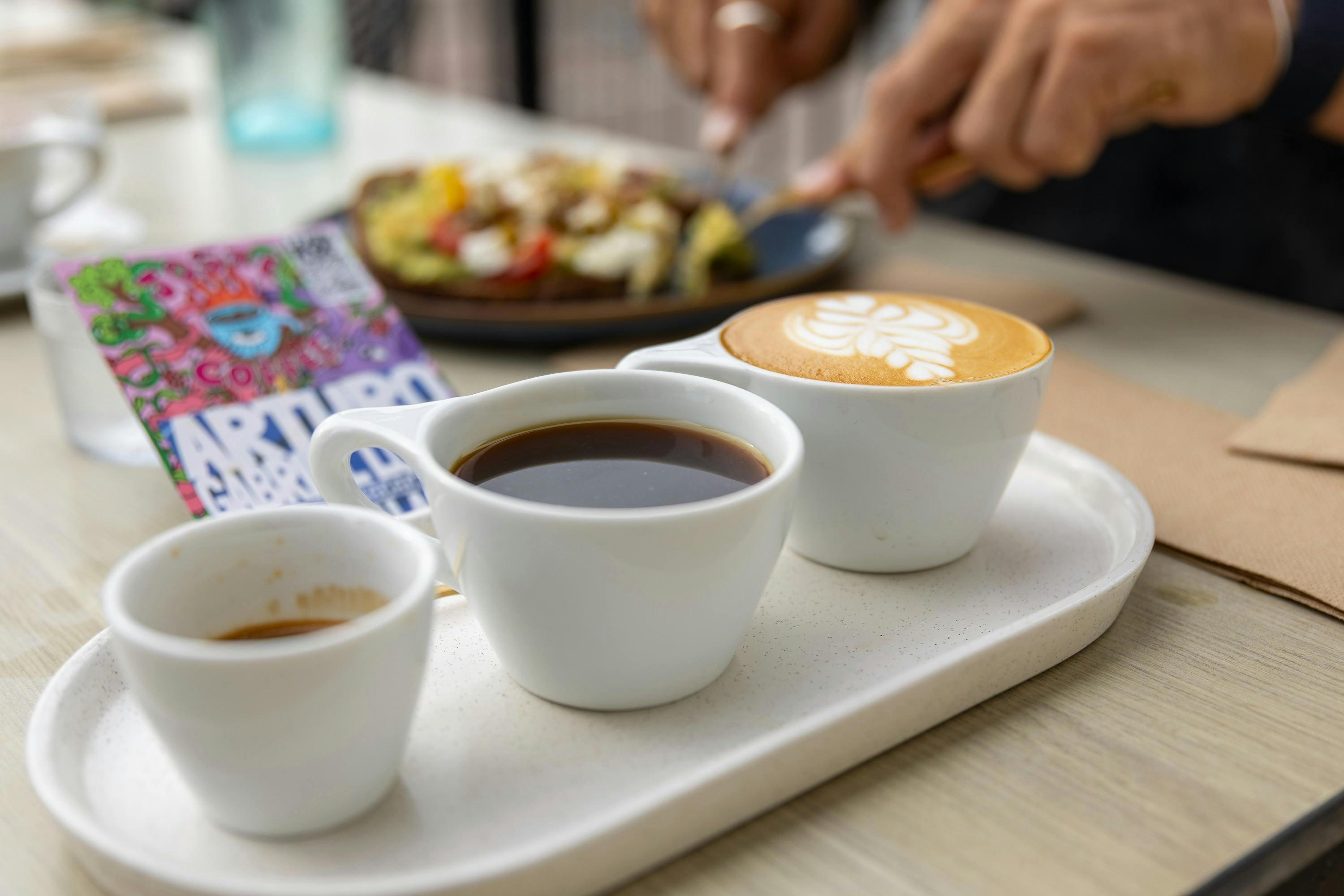 Three coffees sit on a platter, on a table. The accompanying card reads "Arturo Lopez Diaz".
