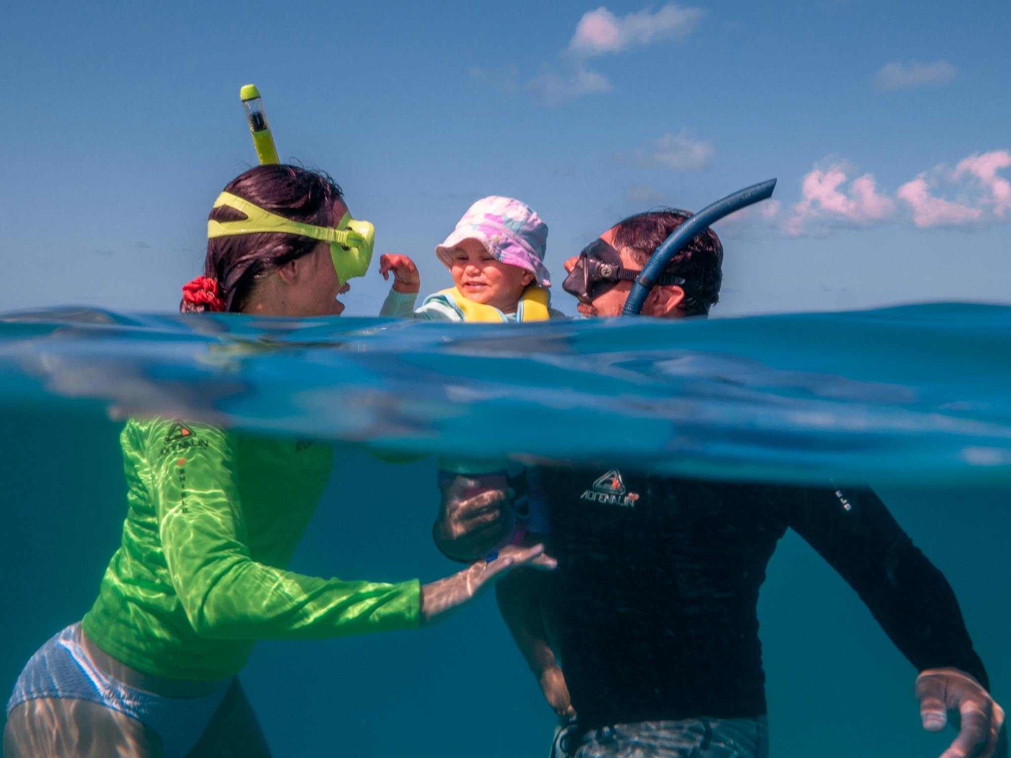 A man and women are snorkelling with their child.