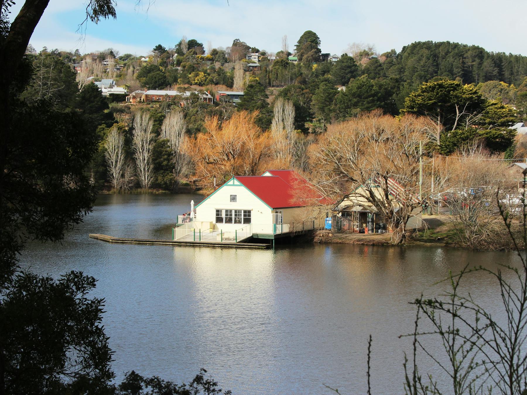 View over lake to red and white boathouse building and jetty