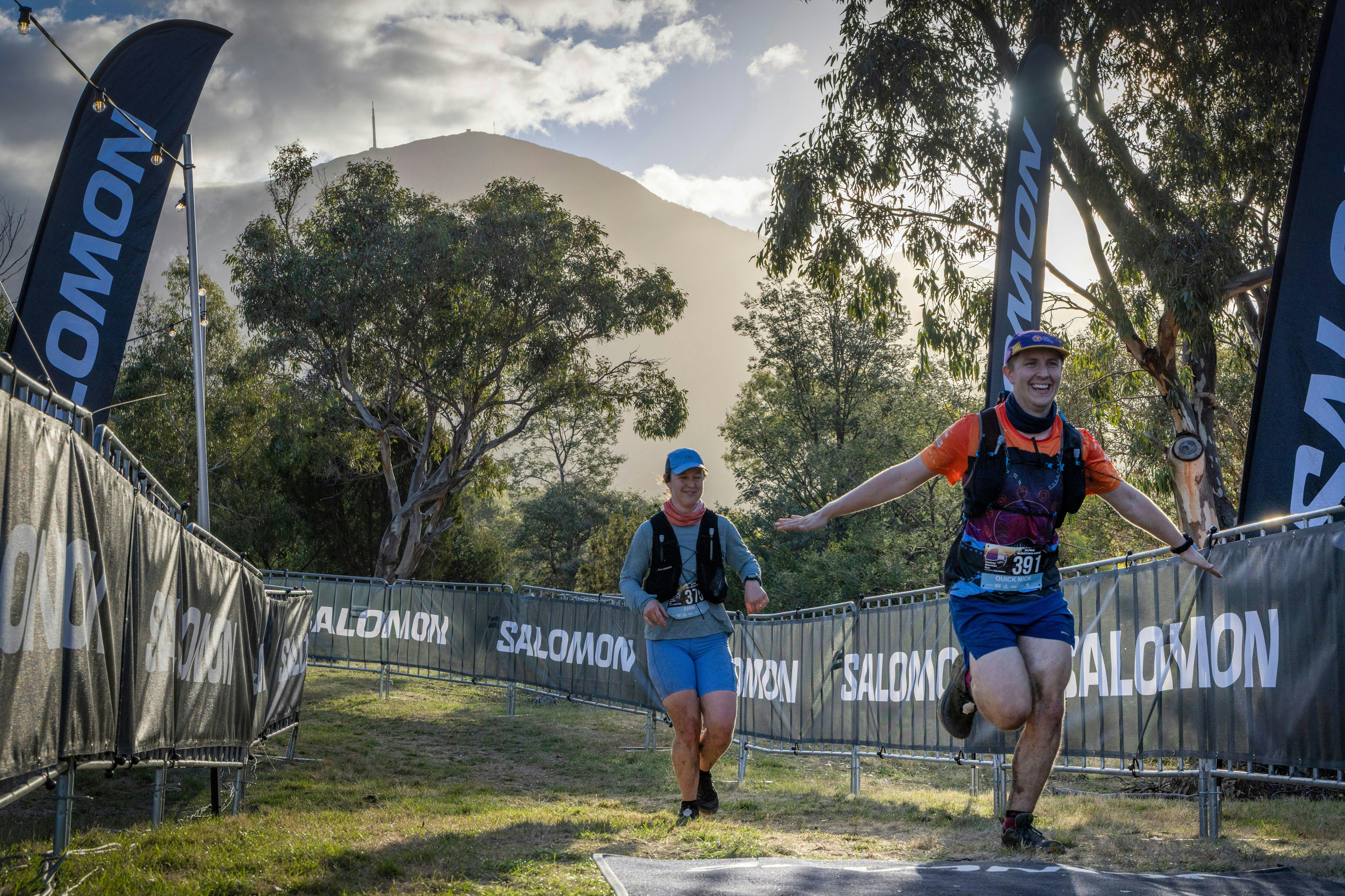 Two runners cross the finish line late in the afternoon with soft light