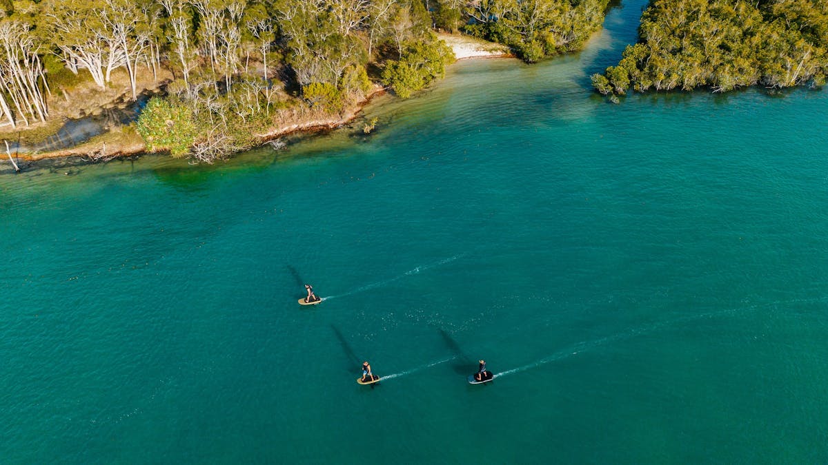 Drone shot of three people Foiling in Noosa Sunshine Coast, blue water and nature  Fliteschool Noosa