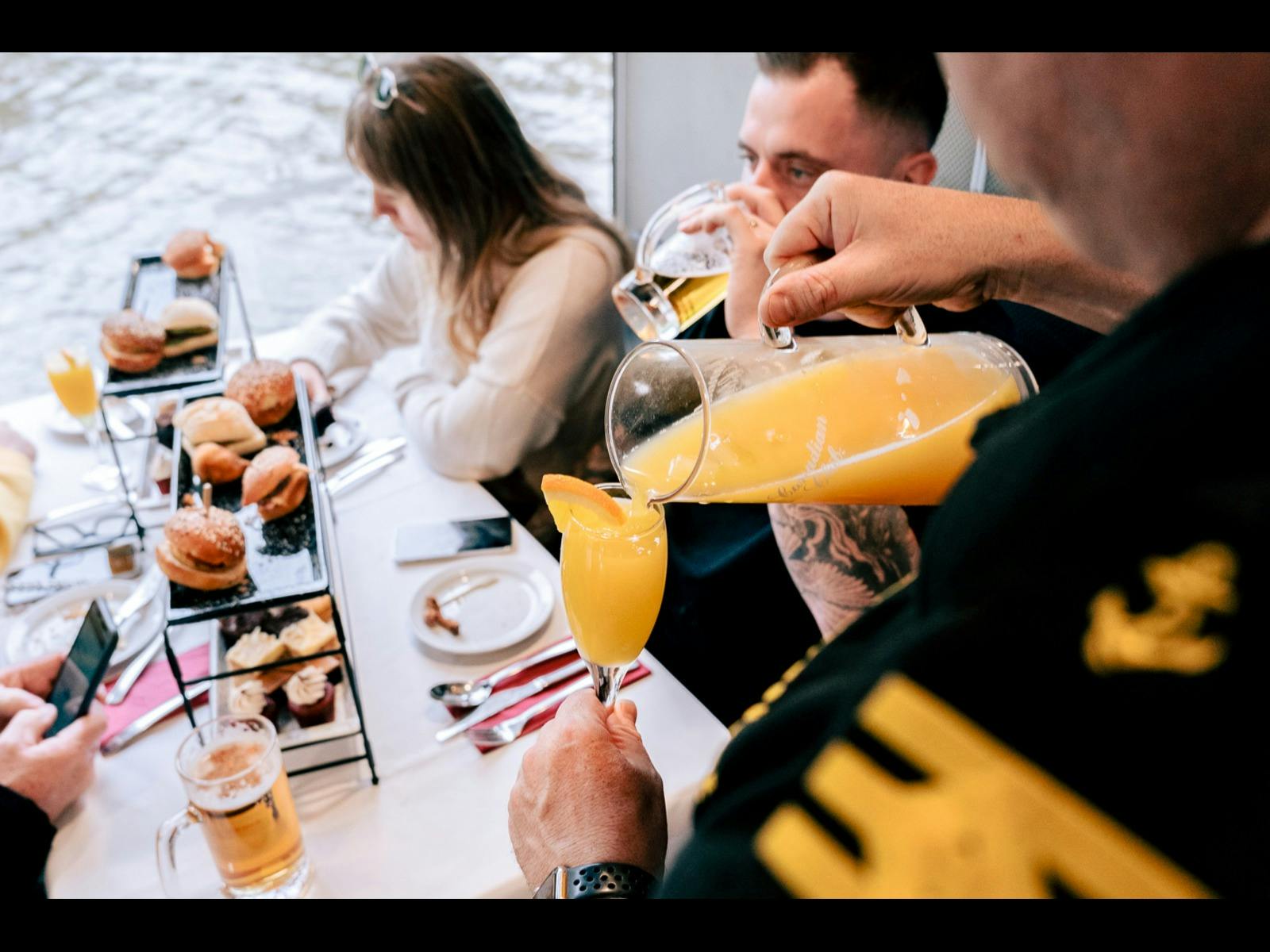 Staff pouring a mimosa for guests with brunch offerings in background