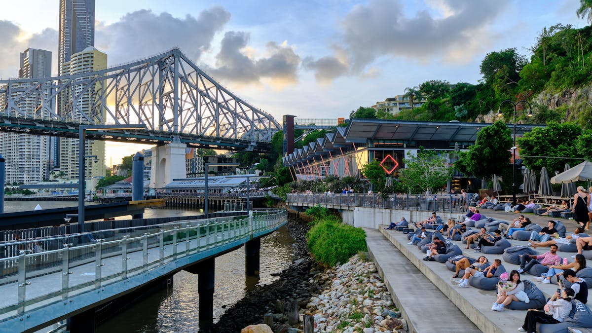 crowd of people relaxing on riverbank in front of Story Bridge