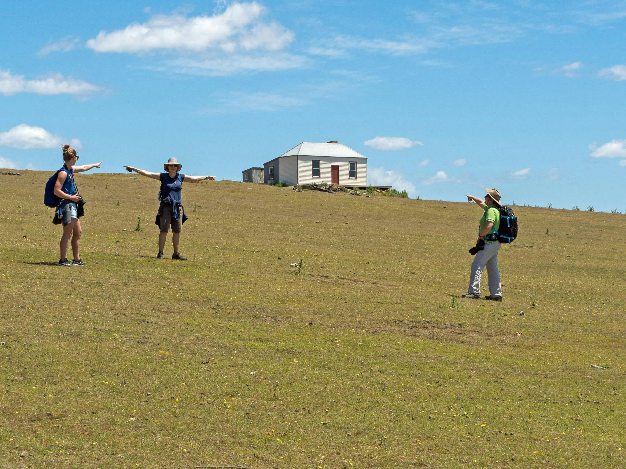 Guests standing on grassy sloping hill with old building on top of hill