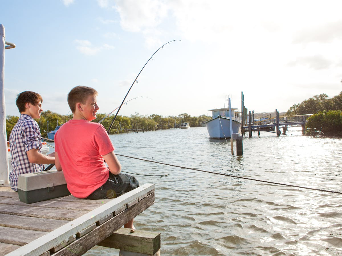 photo showing two boys fishing off a pier on the Great Sandy Strait