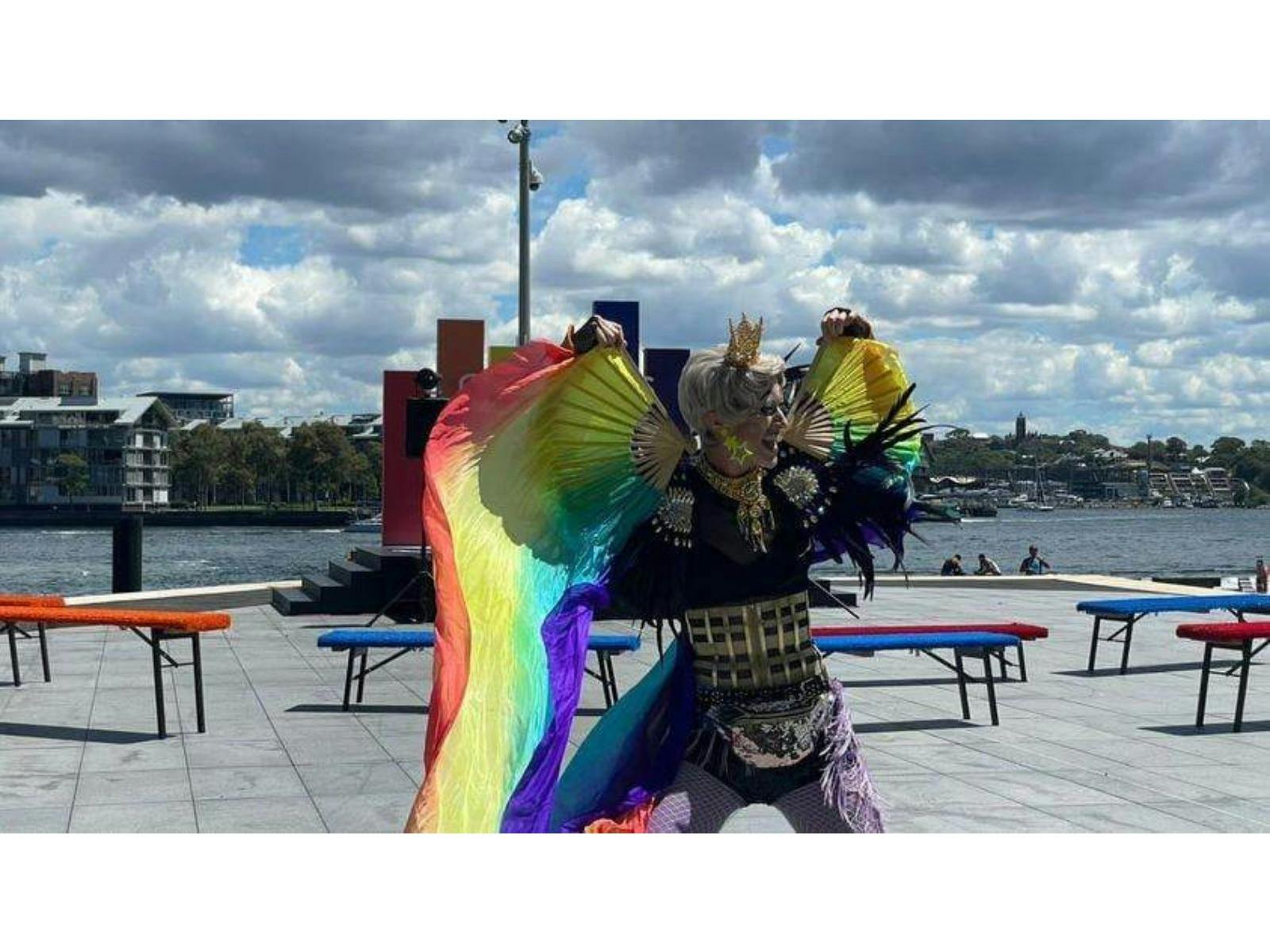 A drag king dances with rainbow fans and silks