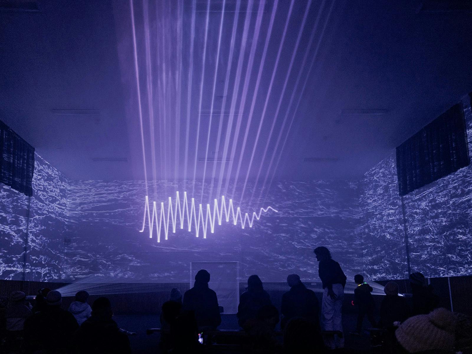 Multiple lines of mauve lights intersect the image taken inside a school  hall.