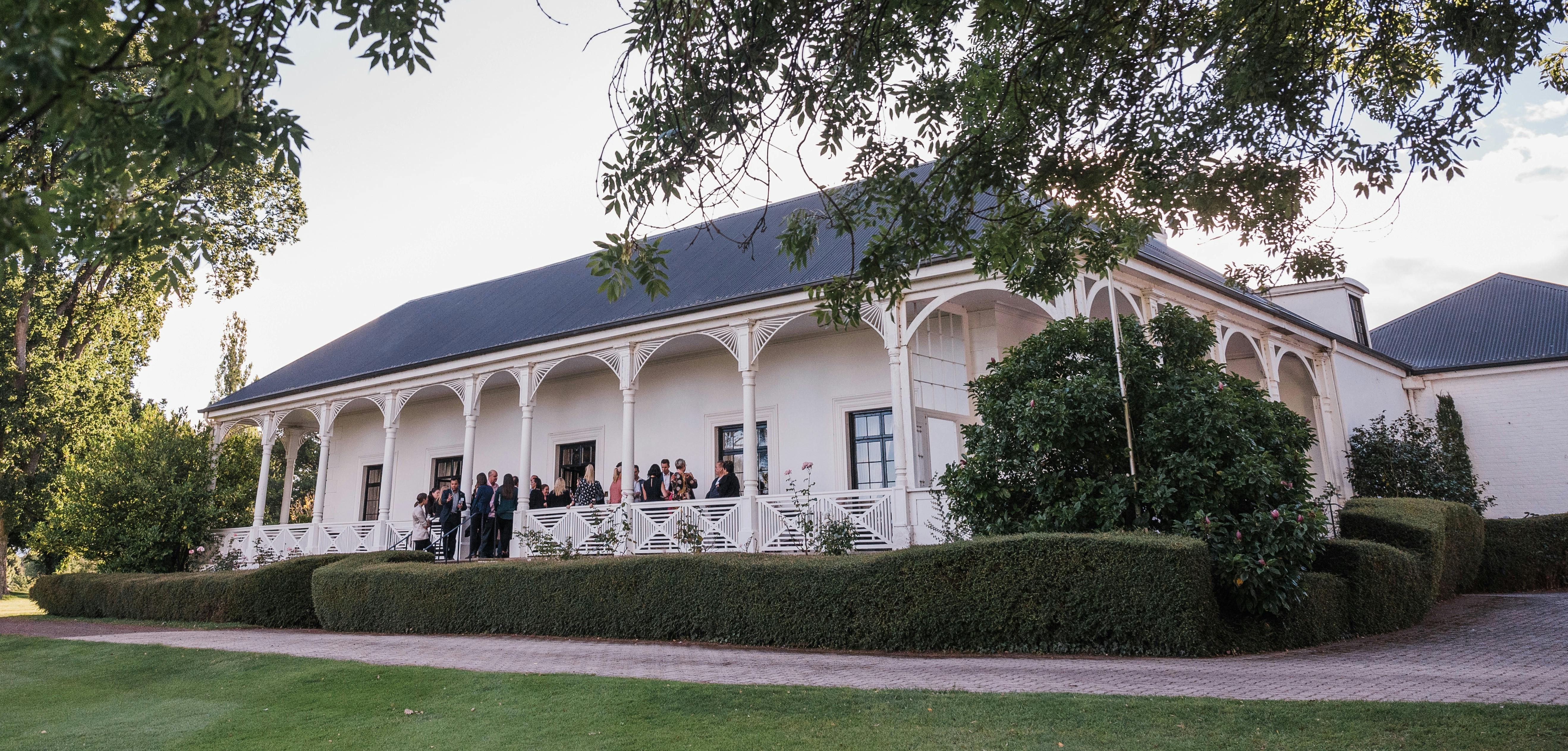 Quamby Homestead, white with elegant arches, behind a box hedge and rose garden