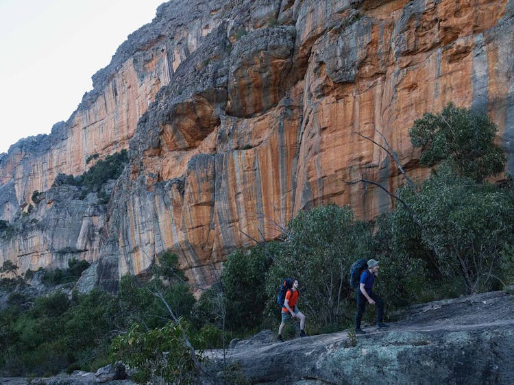 2 hikers in single file ascend a ridgeline
