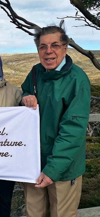 four seniors holding a gang gang tours banner with mountains behind