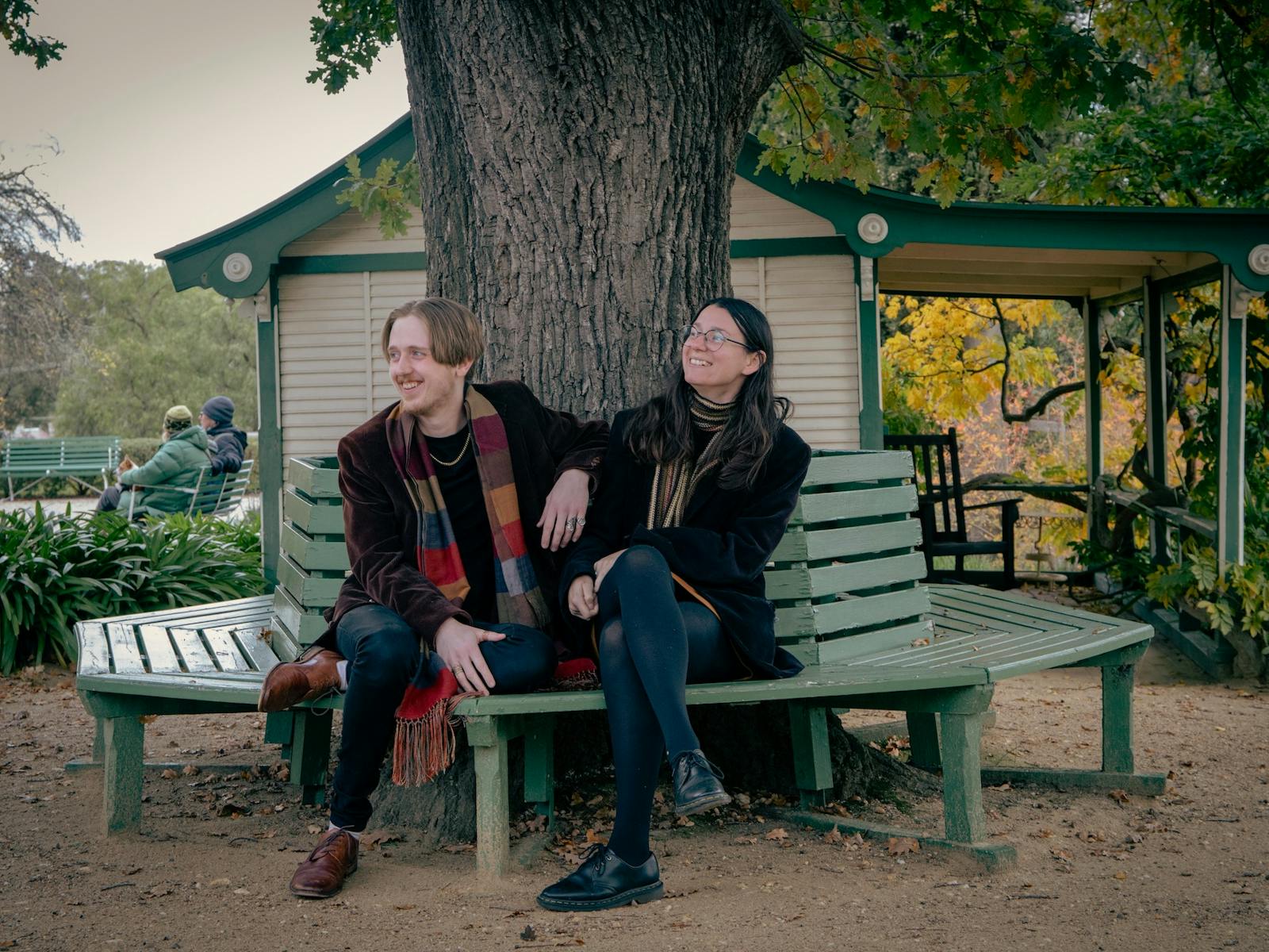 Two people sitting on a bench under the tree