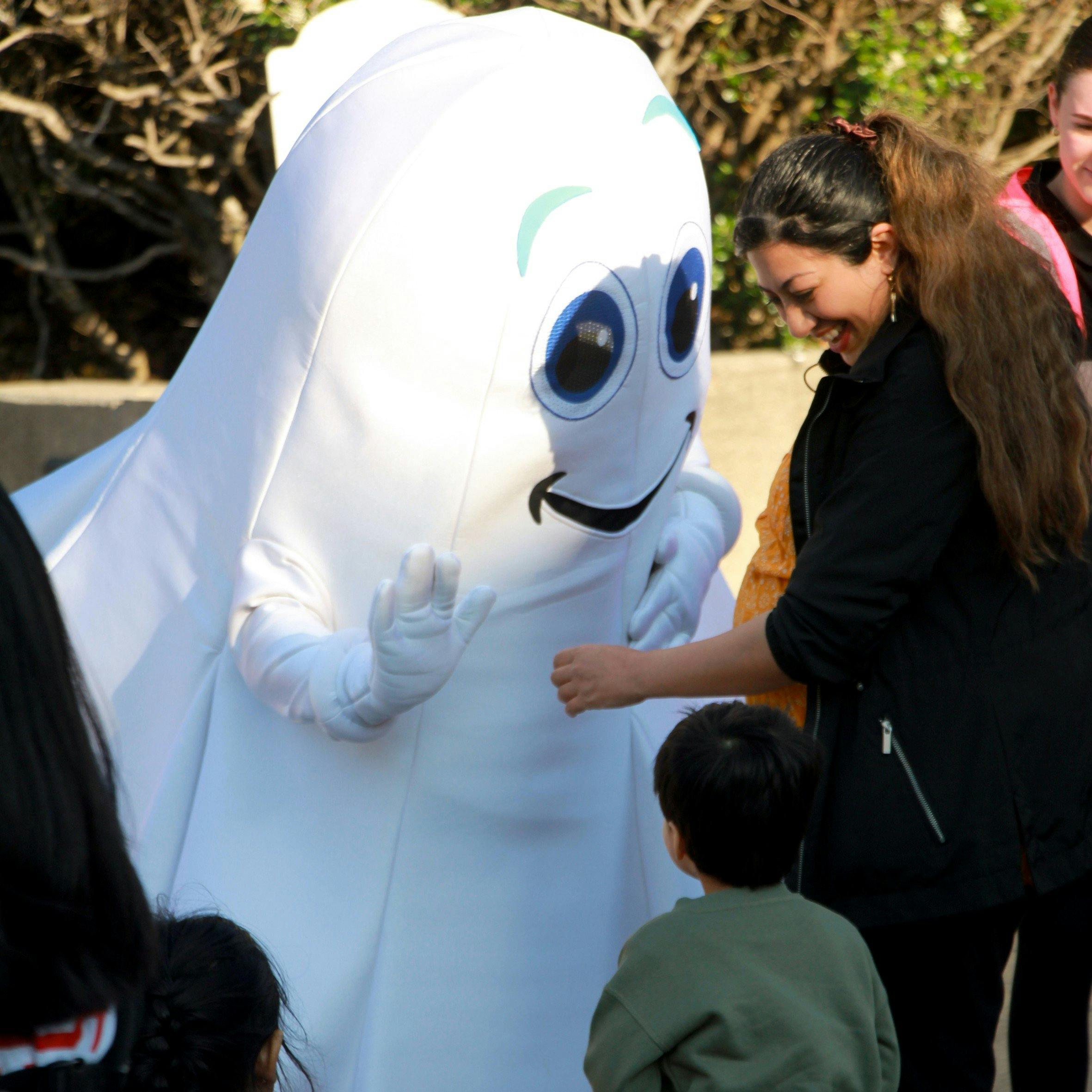 A costumed ghost saying hello to a mother and chaild