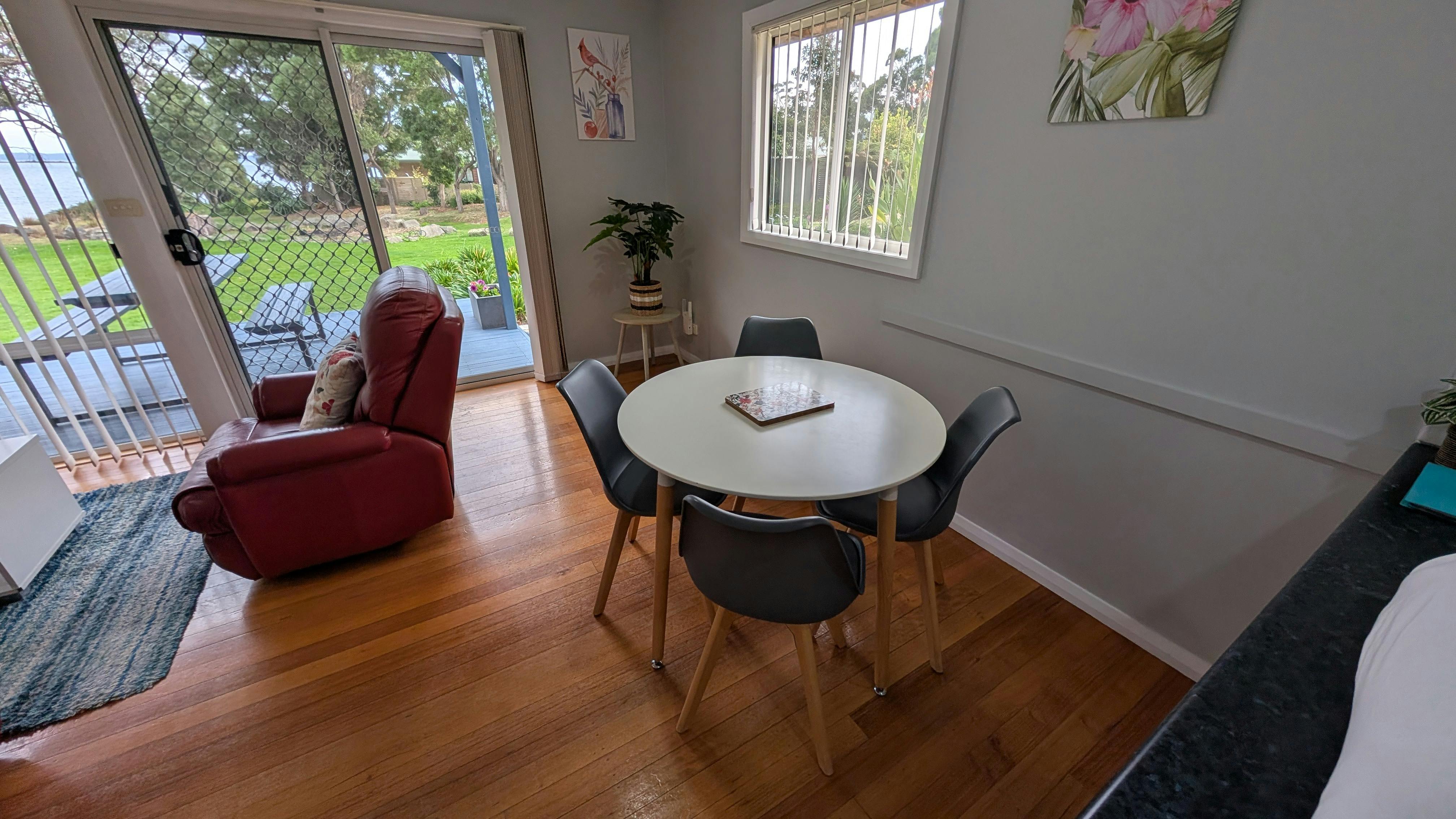 Dining area with round table, timber floors and garden views.