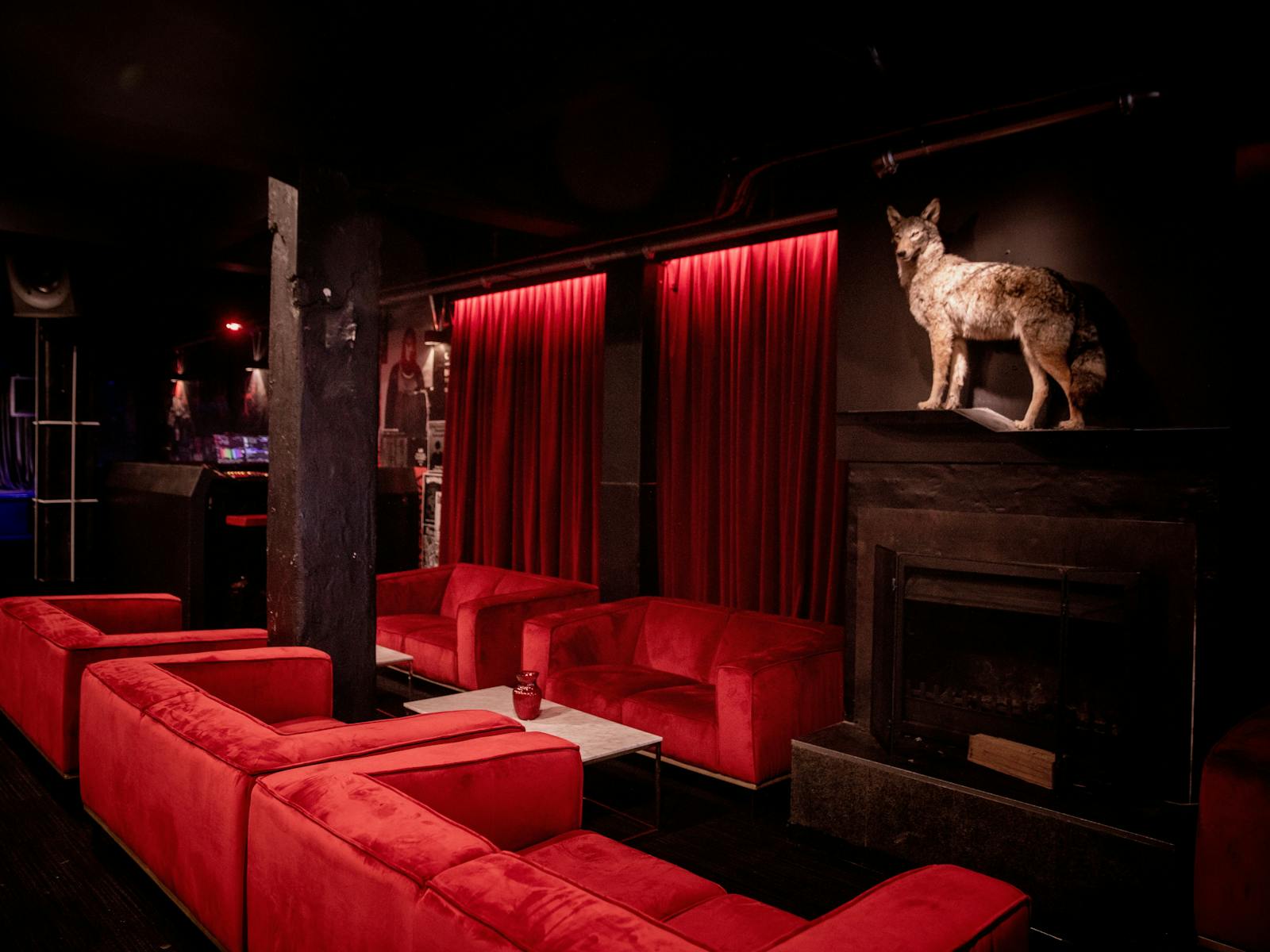 Altar's taxidermy coyote stands above the fireplace in the lounge bar with red velvet couches