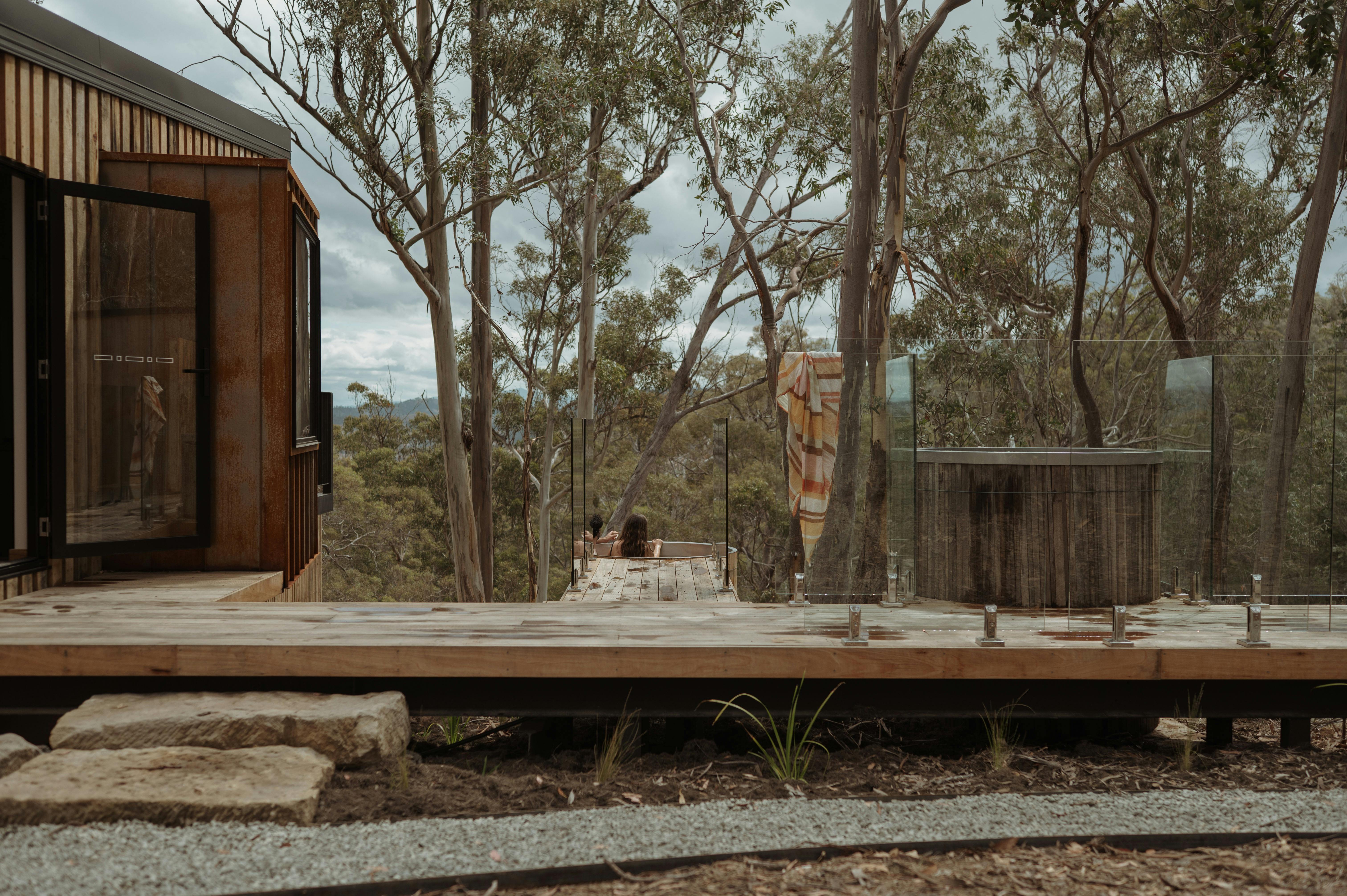 A cabin, hot tub and cold plunge with a view through trees