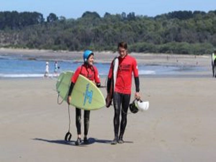 East Coast Surf School - walking on the beach holding boards.