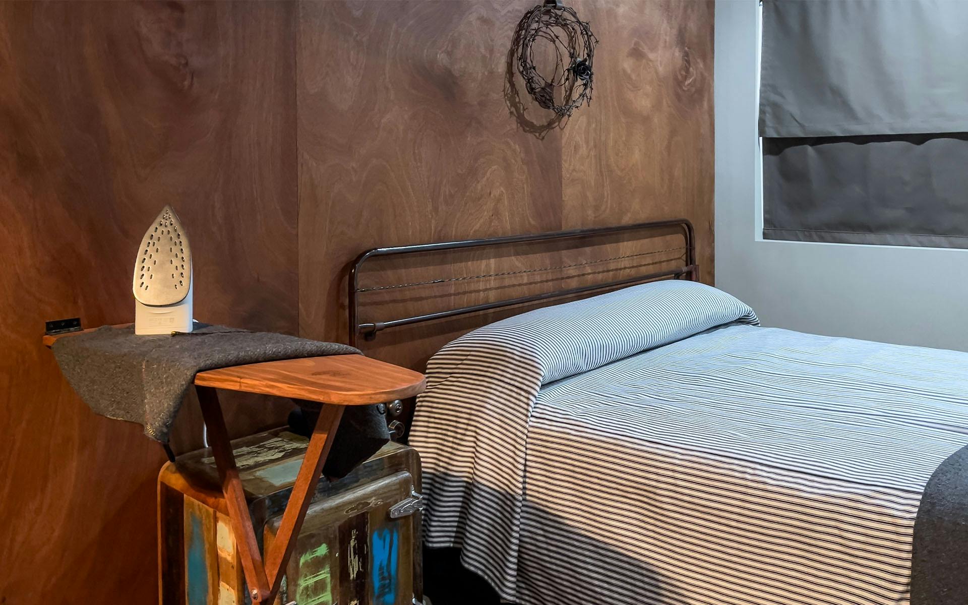 An ironing board set up beside the bed