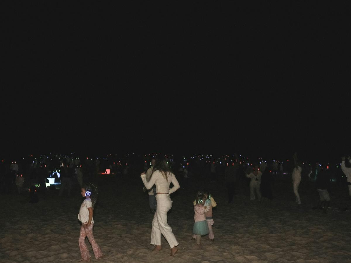 People dancing on the beach at Silent Disco Under the Stars at the 2024 SWELL Sculpture Festival