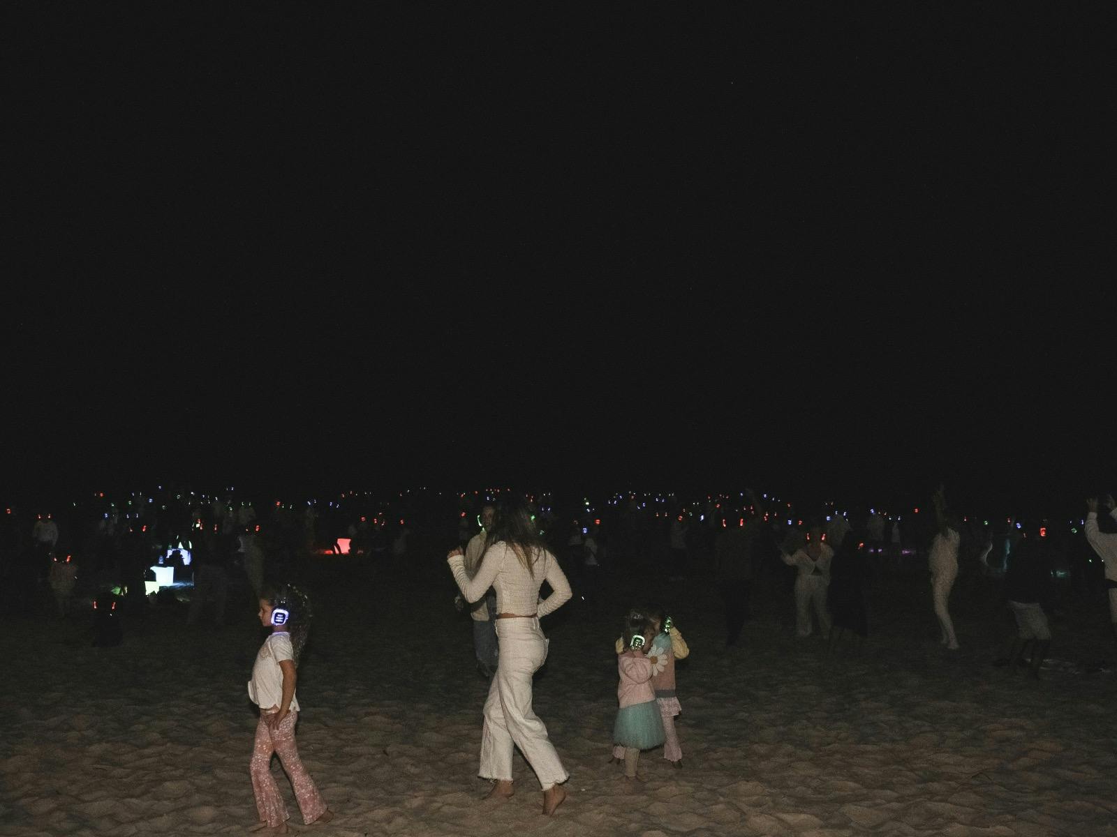 People dancing on the beach at Silent Disco Under the Stars at the 2024 SWELL Sculpture Festival