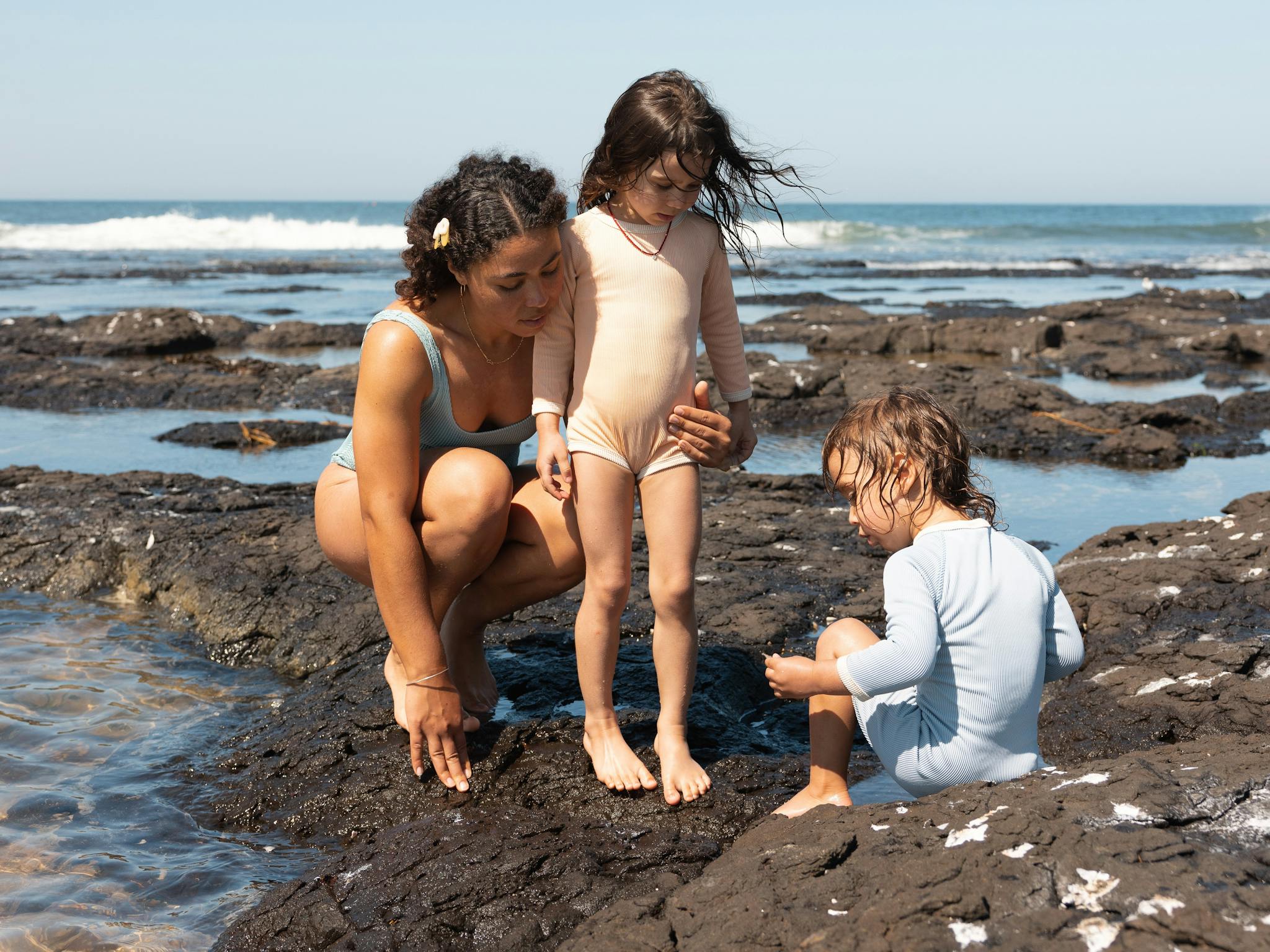 a mum and two young girls exploring the rock pools at Flat Rock