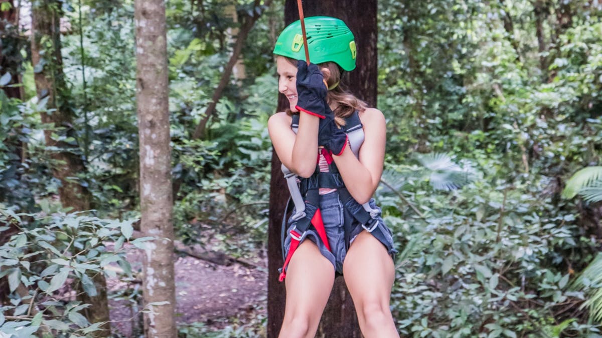 Girl smiling as she zips through the trees
