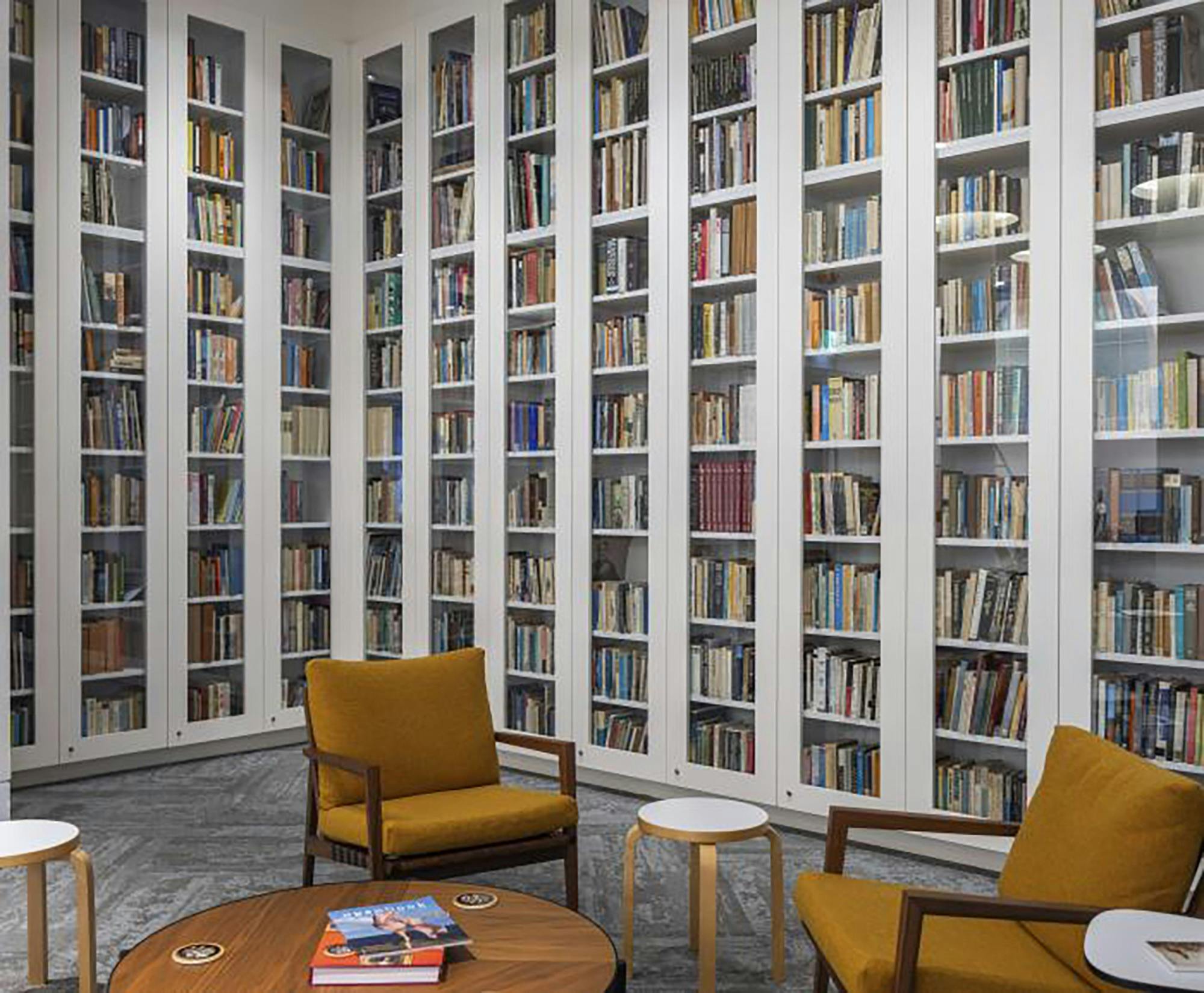 A room with bookshelves lining the walls and a coffee tables and seats