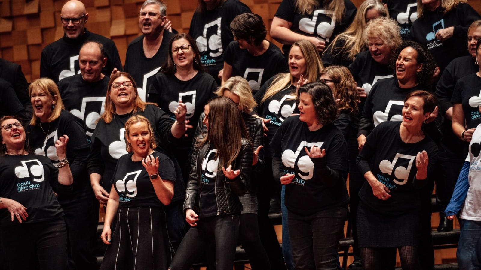 Adult Glee Club members performing with energy at a choir workshop.